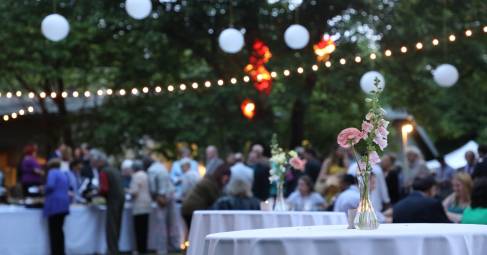 People at a party outdoors under string lights.