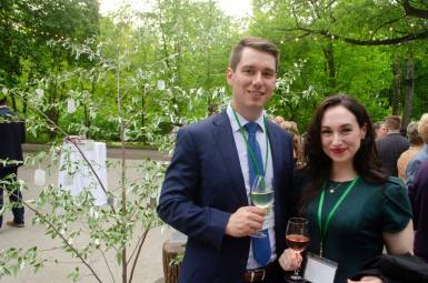 A man and a woman in party clothes smile outdoors.