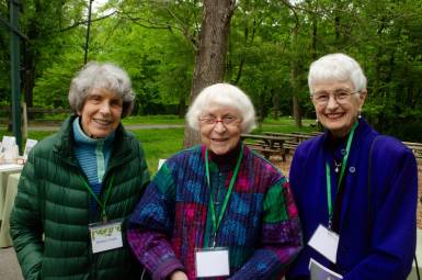 Three women wearing lanyards smile for the camera.