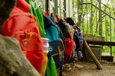 A row of backpacks hanging up outdoors.