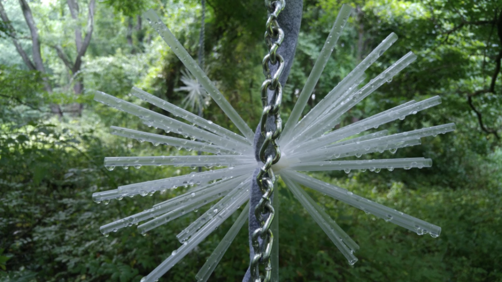 A sculpture of chain and straws outdoors.