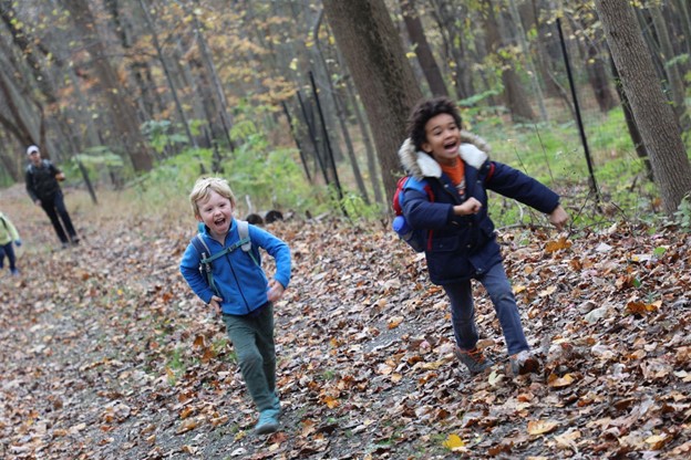 Two children running along an autumn path in a forest. 