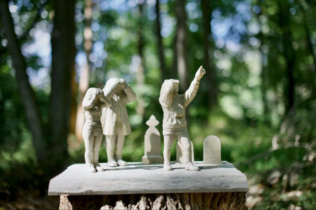 A sculpture of birdwatchers looking upward in a forest.