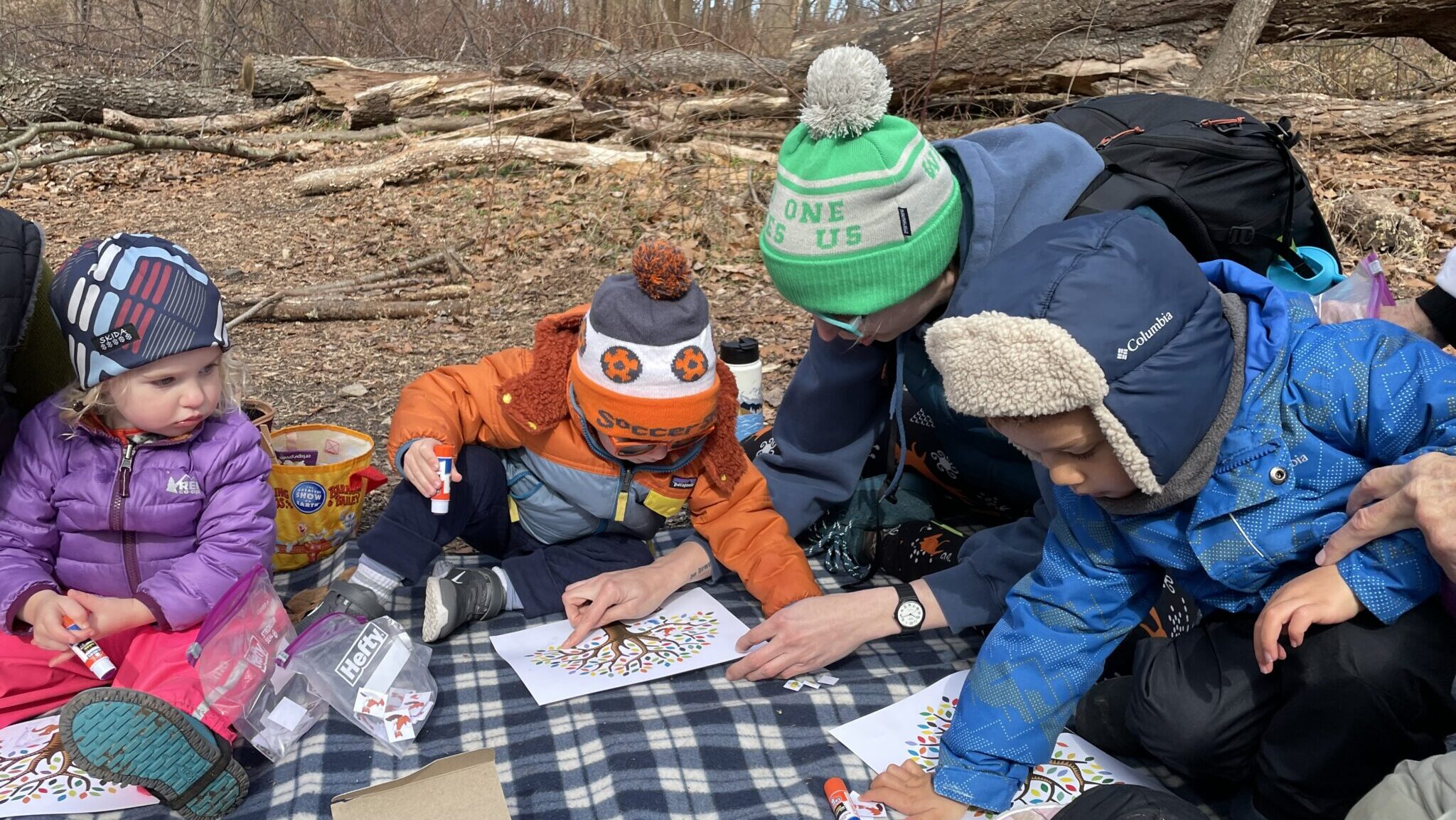 Parents and young children in winter clothing outdoors coloring.