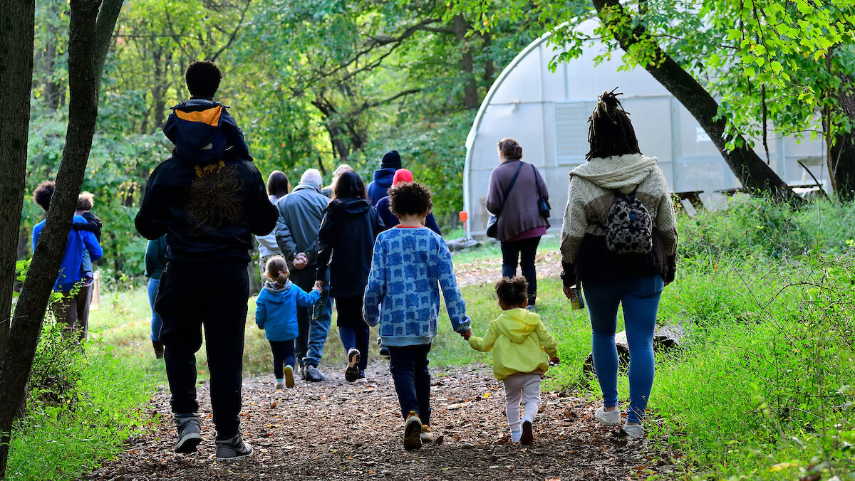 A group of families walks along a dirt trail at the Schuylkill Center.